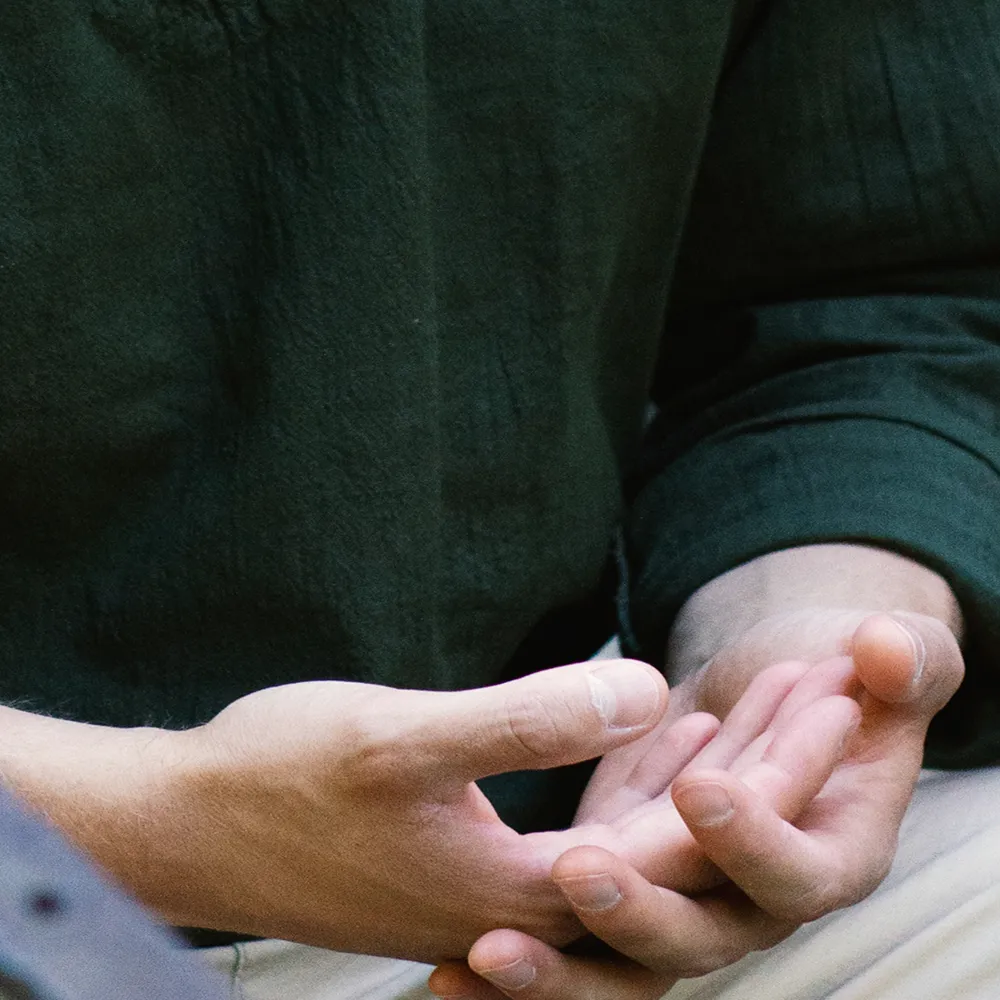Hände liegen in Meditationshaltung auf dem Schoß